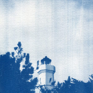 Phare qui surgit parmi les pins maritimes avec le ciel un peu contrasté en arrière-plan.