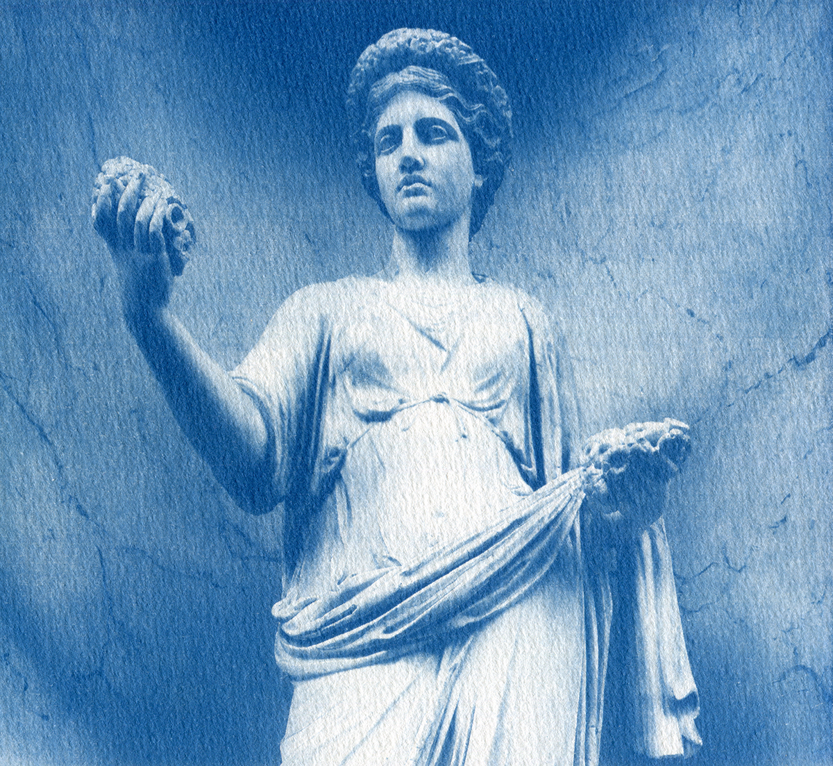 Statue qui représente la déesse romaine Flore au musée du Louvre. Le fond est marbré et la statue est vêtue d'une toge et d'une tiare fleurie. Elle tient un fruit dans chaque main.