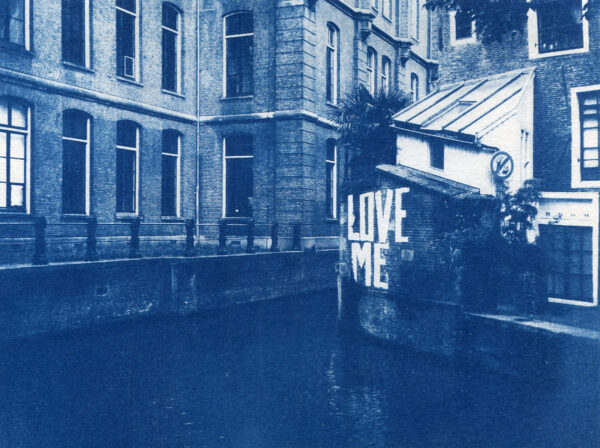 Vieil immeuble et morceau de canal d'Amsterdam avec le graffiti "Love Me" sur l'un des murs.