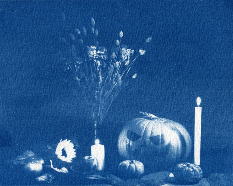 Verso de ma nature morte qui représente une grosse citrouille avec les yeux et le sourire façon Halloween, ainsi que deux autres mini citrouilles, des bougies allumées, un bouquet de fleurs séchées, un tournesol, des pommes et des feuilles mortes.