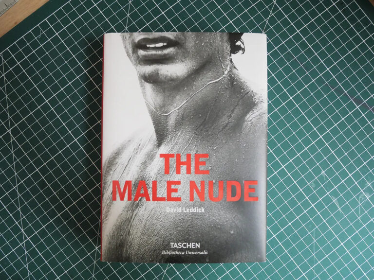 Couverture du livre The Male Nude aux éditions Taschen. Derrière le titre en rouge est représenté un homme torse nu en noir et blanc et dont on ne voit que le bas du visage.