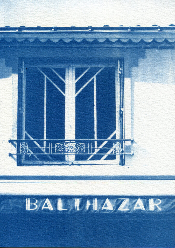 Fenêtre aux carreaux art et le store banne du café où il est écrit "Balthazar".