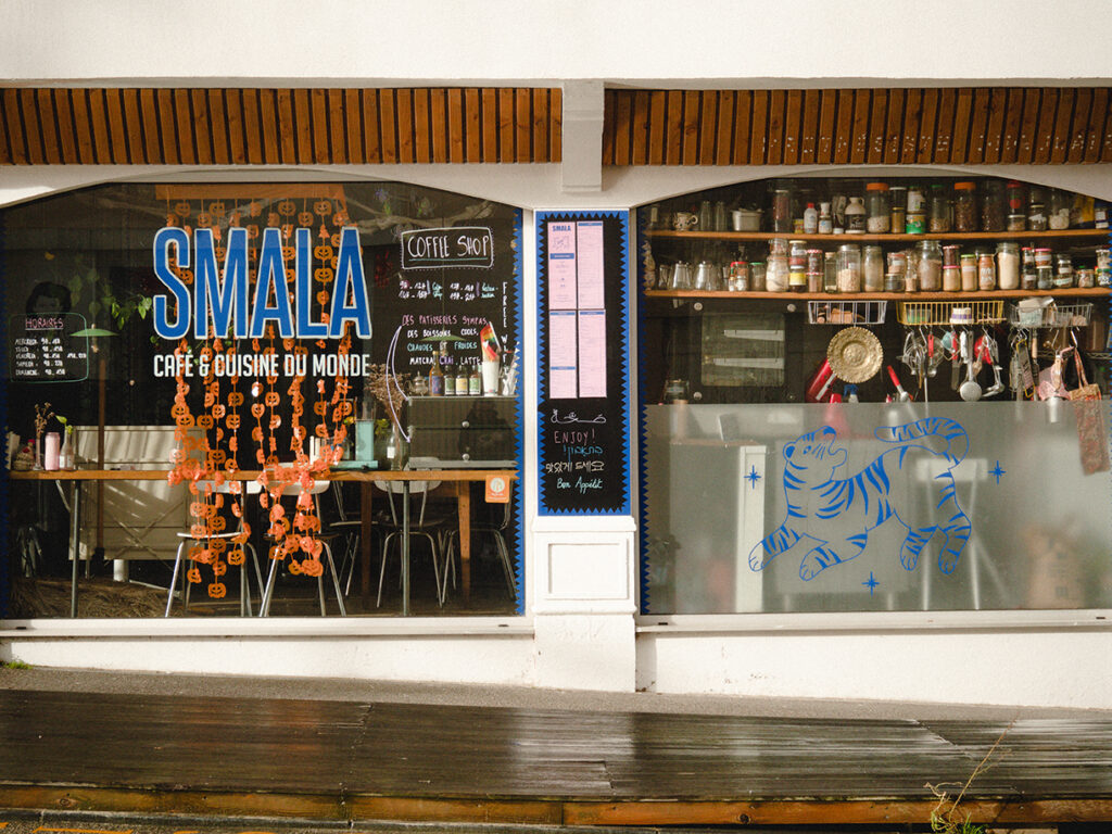 Devanture du restaurant Smala avec des décorations d'Halloween sur la vitrine. On aperçoit la cuisine et ses multiples ustensiles à travers la vitre.