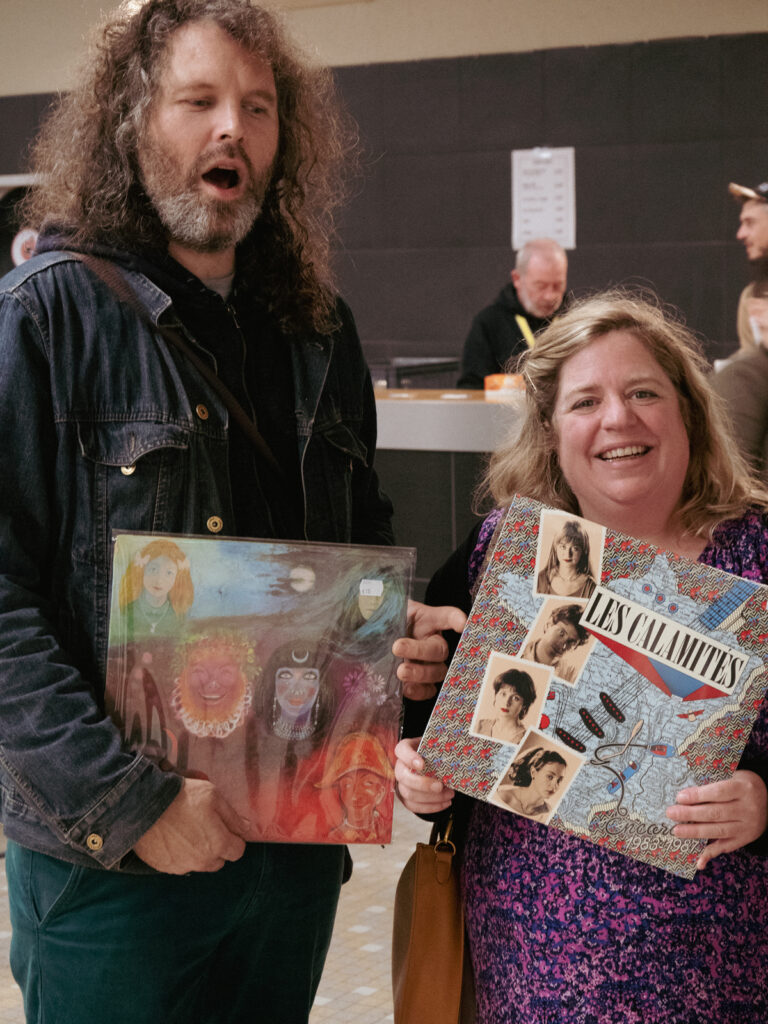 Un homme et une femme face à l'objectif, tenant les vinyles qu'ils viennent d'acheter.