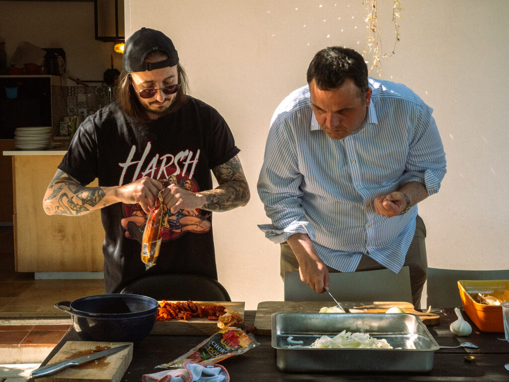 Deux hommes en train de faire la cuisine sur une table d'extérieur.