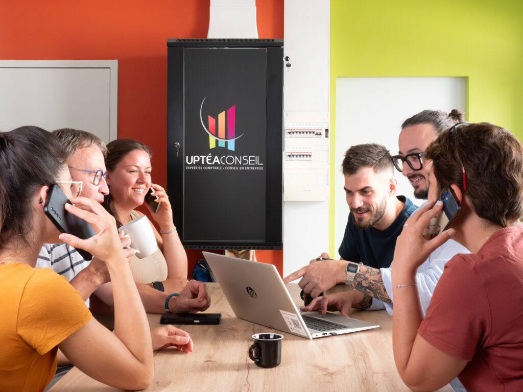 Un groupe de 6 collègues autour d'une table et en train de travailler avec le sourire.