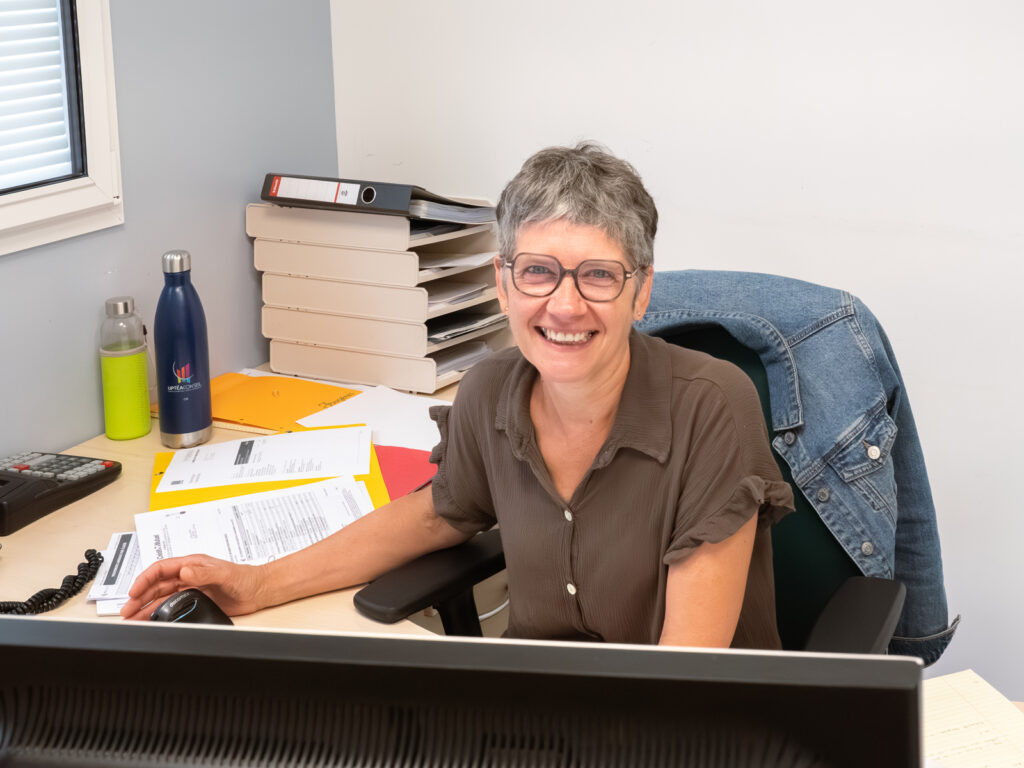 Portrait d'une employée d'entreprise derrière son bureau en train de travailler avec un grand sourire.